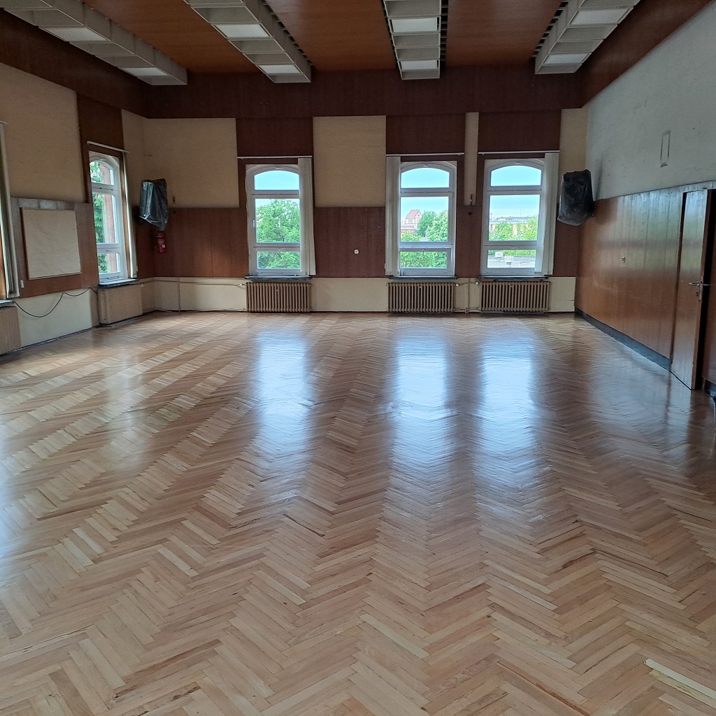 Aula XIV LO w Szczecinie po zakończeniu prac - parkiet jest odnowiony i błyszczy w słonecznym świetle